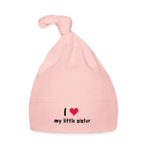 Licht roze babymuts met een knoop bovenaan en de tekst 'I ♥ my little sister' in zwarte en rode letters.