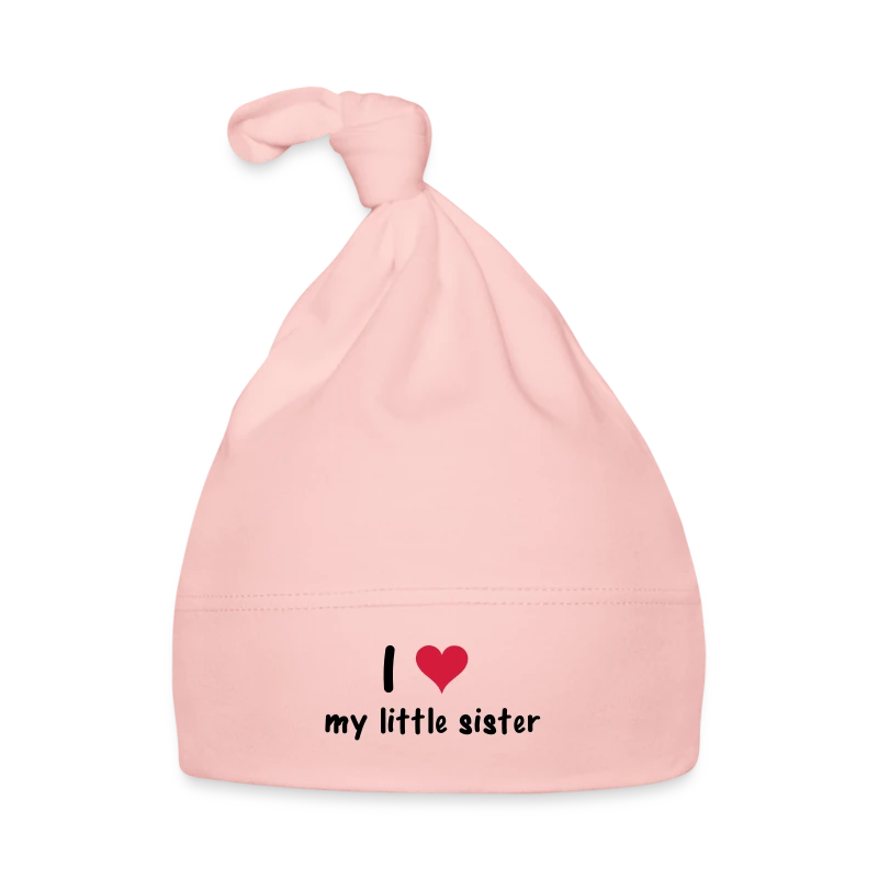 Licht roze babymuts met een knoop bovenaan en de tekst 'I ♥ my little sister' in zwarte en rode letters.